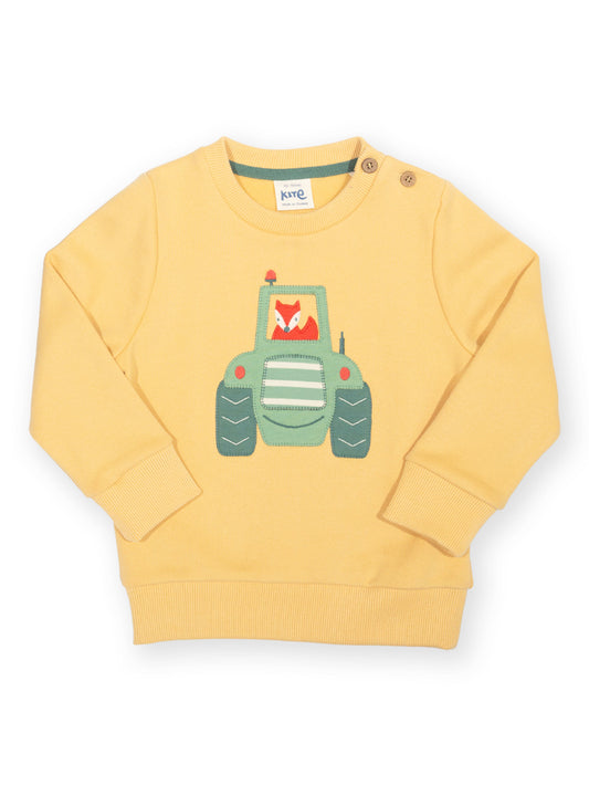 A pale yellow long-sleeve baby sweatshirt featuring a green cartoon tractor graphic on the front, with a small fox illustration inside the tractor window. The sweatshirt has a ribbed crew neck, cuffs, and hem, and is photographed flat against a white background.