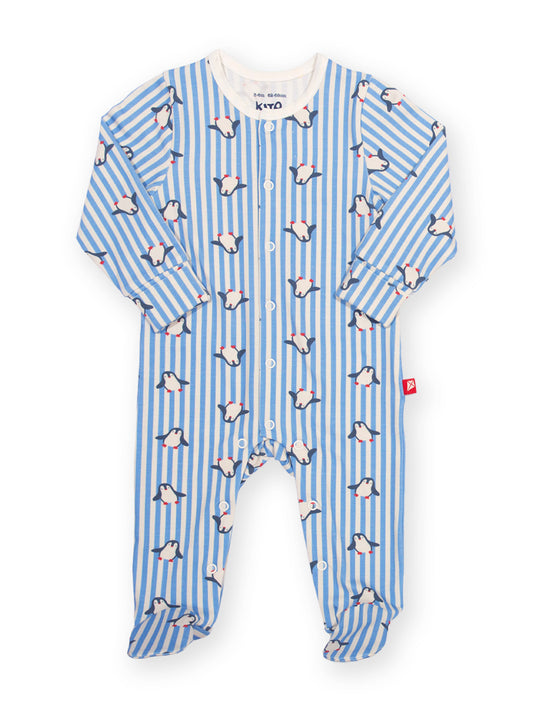 A baby footed sleeper with long sleeves and an all-over print of penguins on a light blue and white striped background, shown flat on a white background.