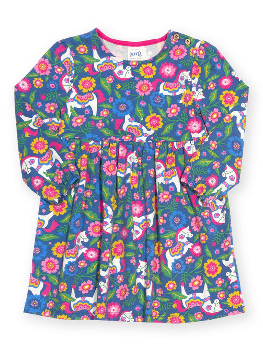 A long-sleeve children's dress with a vibrant, colorful print featuring white cats, pink and yellow flowers, and green leaves on a blue background. The brand name 'kng' is visible on the inner neck label.